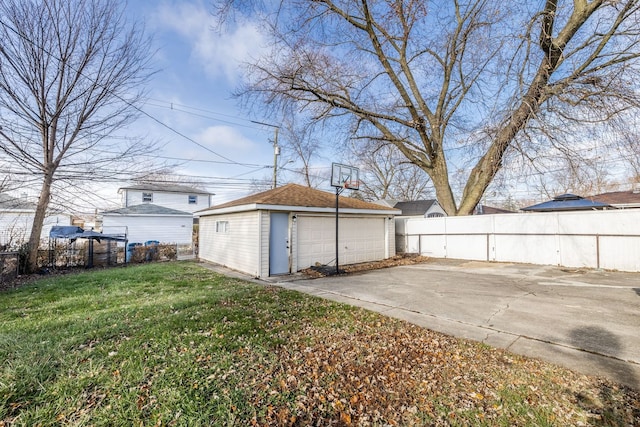 exterior space with fence private yard, a detached garage, a lawn, and an outdoor structure