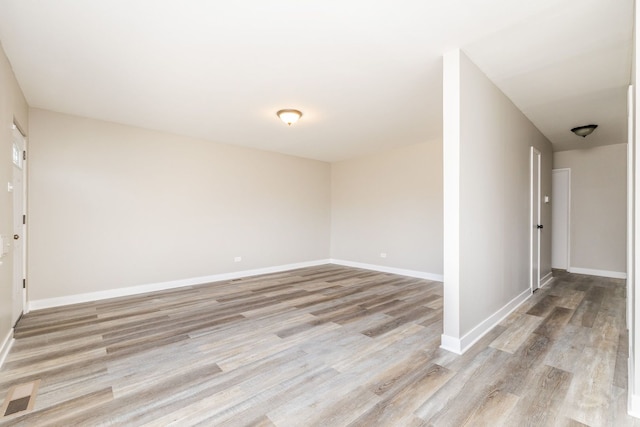 spare room featuring light wood-type flooring, visible vents, and baseboards