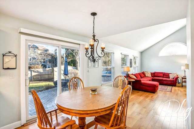 dining space featuring light hardwood / wood-style floors, vaulted ceiling, and a notable chandelier