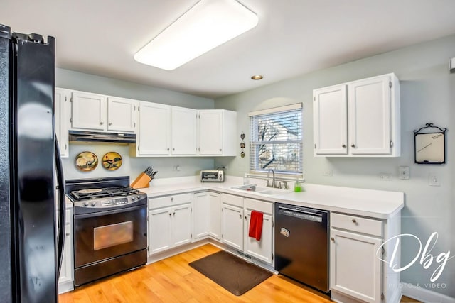 kitchen with black appliances, white cabinets, light wood-type flooring, and sink