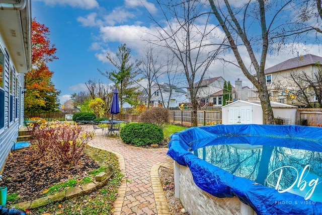 view of yard featuring a patio area, a covered pool, and a storage unit