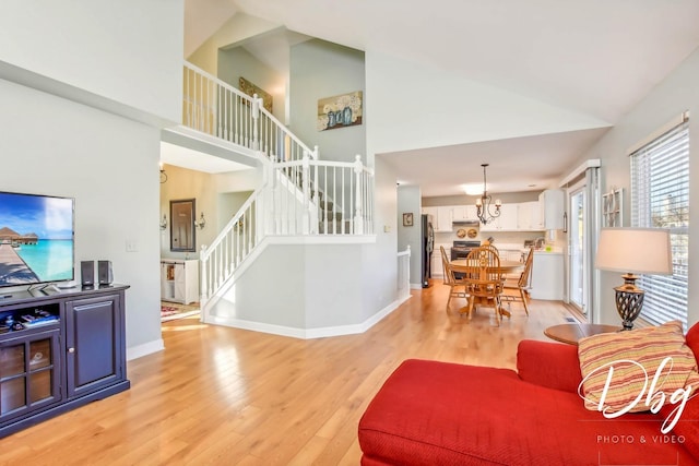 living room featuring a chandelier, high vaulted ceiling, and light hardwood / wood-style flooring