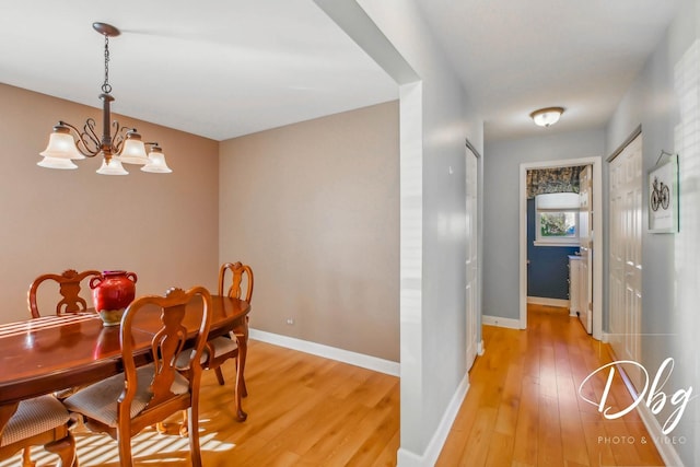 dining room featuring light wood-type flooring and an inviting chandelier