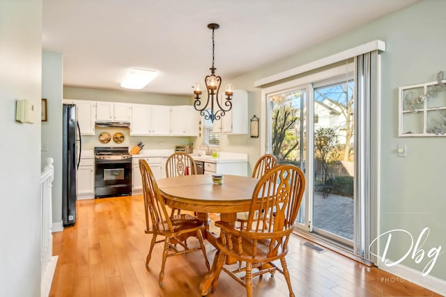 dining space featuring light wood-type flooring and an inviting chandelier