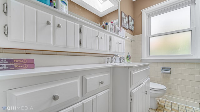 bathroom featuring toilet, tile walls, and sink