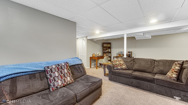 living room featuring a drop ceiling and light colored carpet