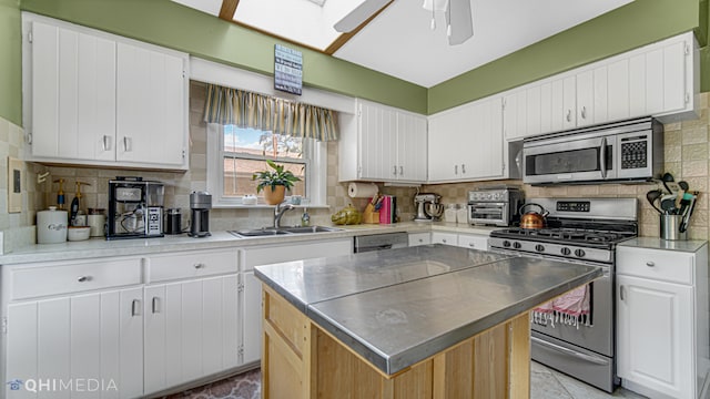 kitchen with a skylight, white cabinetry, sink, and stainless steel appliances