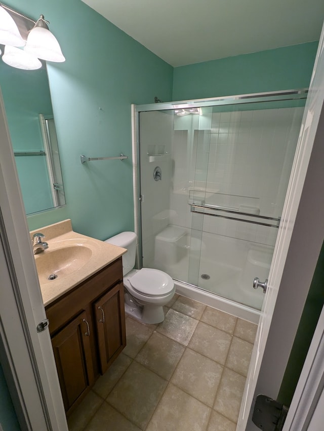 bathroom featuring tile patterned floors, toilet, an enclosed shower, and vanity