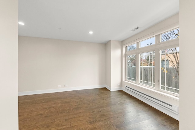 spare room featuring baseboard heating and dark wood-type flooring