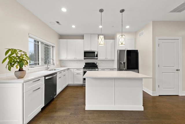 kitchen featuring sink, dark wood-type flooring, decorative light fixtures, white cabinets, and appliances with stainless steel finishes