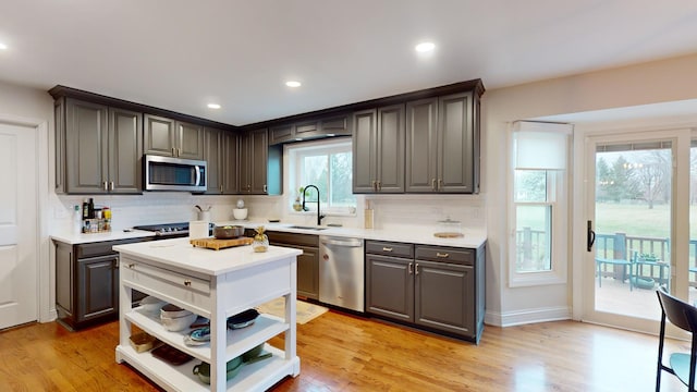 kitchen featuring stainless steel appliances, sink, decorative backsplash, and light hardwood / wood-style flooring