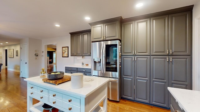 kitchen featuring gray cabinetry, stainless steel fridge, backsplash, and light hardwood / wood-style flooring