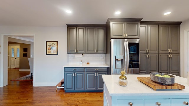 kitchen featuring gray cabinetry, stainless steel fridge with ice dispenser, hardwood / wood-style flooring, and backsplash