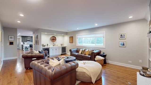 living room with wine cooler, light hardwood / wood-style floors, and indoor wet bar