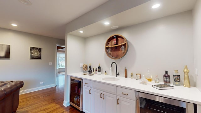 bar featuring white cabinetry, sink, hardwood / wood-style flooring, and beverage cooler