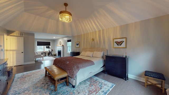 bedroom featuring wood-type flooring, lofted ceiling, and a chandelier