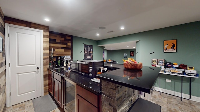 kitchen featuring sink, beverage cooler, wooden walls, and kitchen peninsula