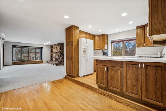 kitchen with a fireplace, light hardwood / wood-style floors, and white refrigerator with ice dispenser