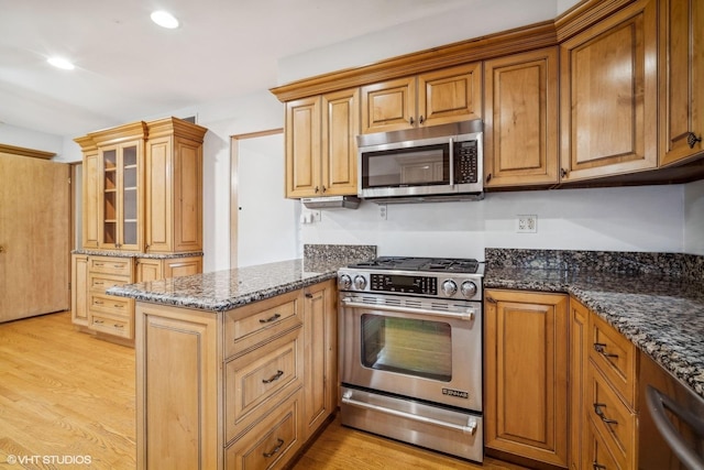 kitchen featuring kitchen peninsula, dark stone countertops, light wood-type flooring, and stainless steel appliances