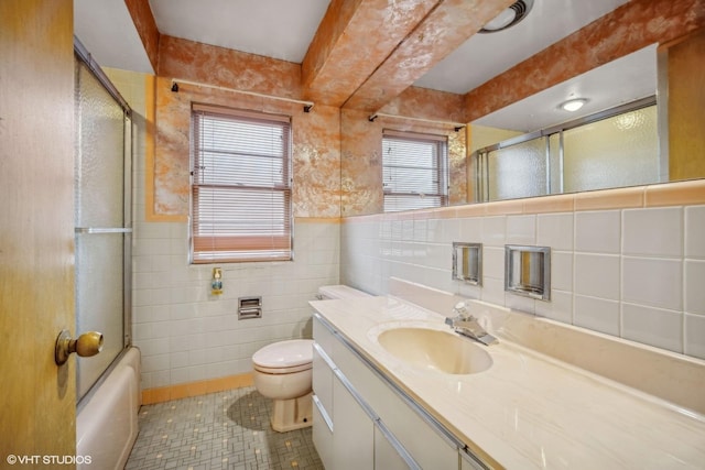 full bathroom with vanity, toilet, shower / bath combination with glass door, and tile walls