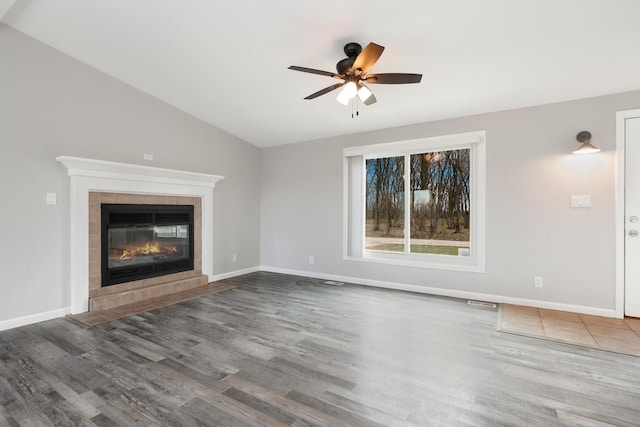 unfurnished living room featuring lofted ceiling, ceiling fan, wood-type flooring, and a tile fireplace