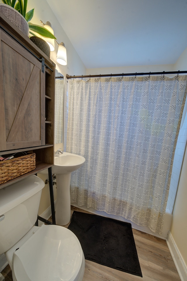 bathroom featuring wood-type flooring, toilet, and shower / bath combination with curtain