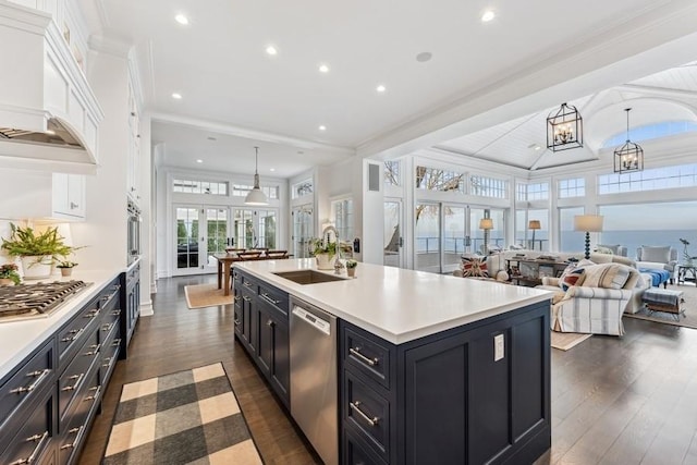 kitchen with pendant lighting, white cabinetry, stainless steel appliances, sink, and a center island with sink