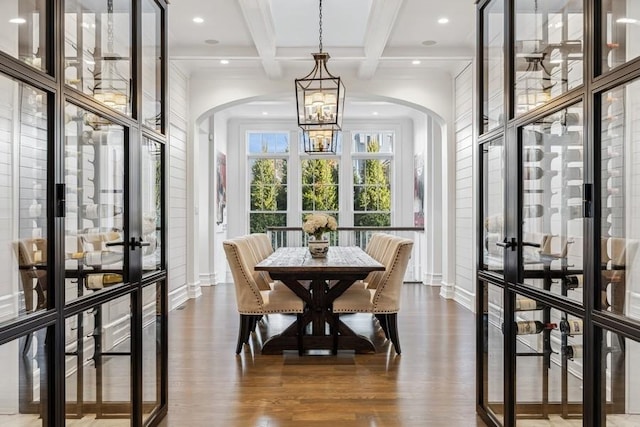 dining room featuring wood-type flooring, french doors, an inviting chandelier, beam ceiling, and coffered ceiling