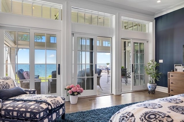 bedroom featuring wood-type flooring, french doors, ornamental molding, access to outside, and a water view