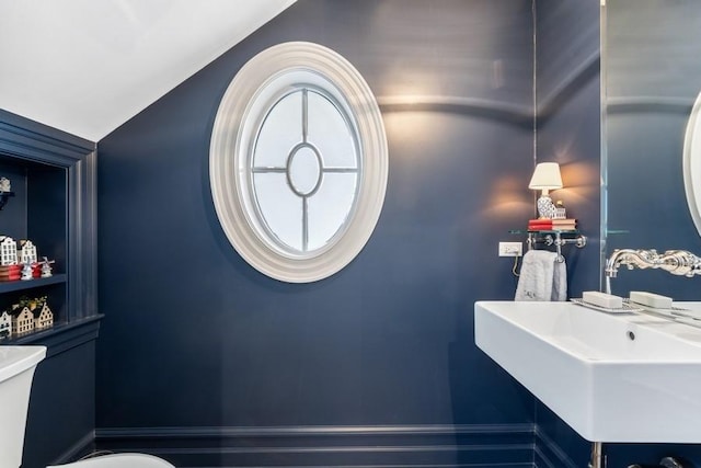 bathroom featuring toilet, vaulted ceiling, and sink