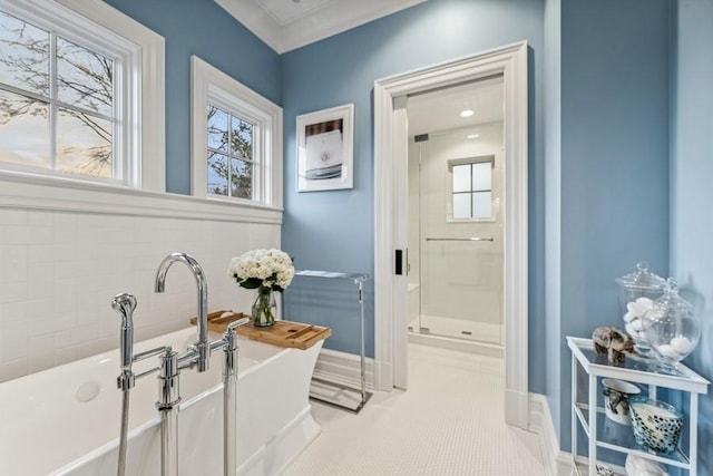 bathroom featuring tile patterned flooring, a tub to relax in, crown molding, and a healthy amount of sunlight