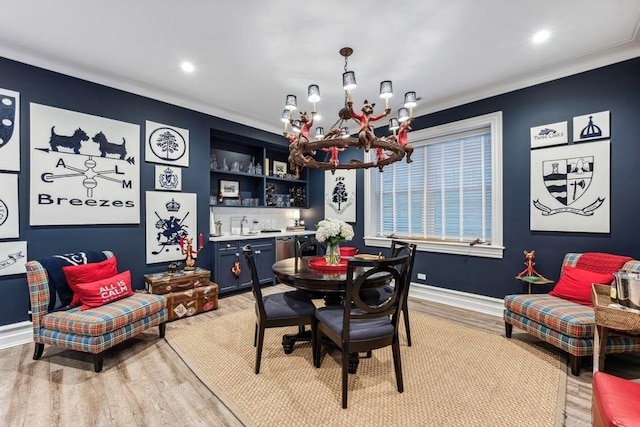 dining area featuring a chandelier, ornamental molding, light hardwood / wood-style flooring, and bar area