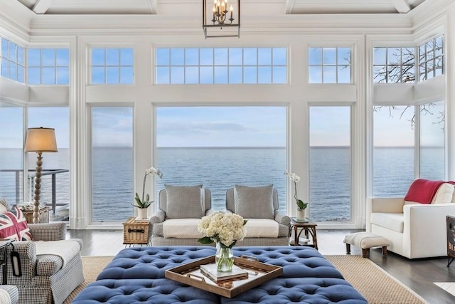 sunroom with a water view and an inviting chandelier