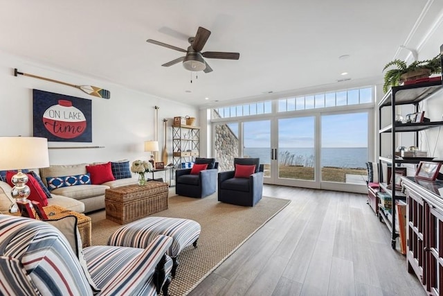 living room with light hardwood / wood-style flooring, expansive windows, a water view, and a healthy amount of sunlight