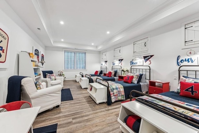 bedroom featuring a raised ceiling, ornamental molding, and light hardwood / wood-style floors