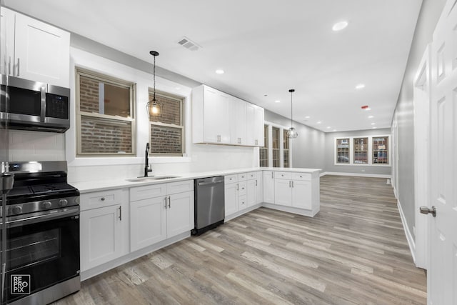 kitchen with white cabinets, decorative light fixtures, sink, and stainless steel appliances