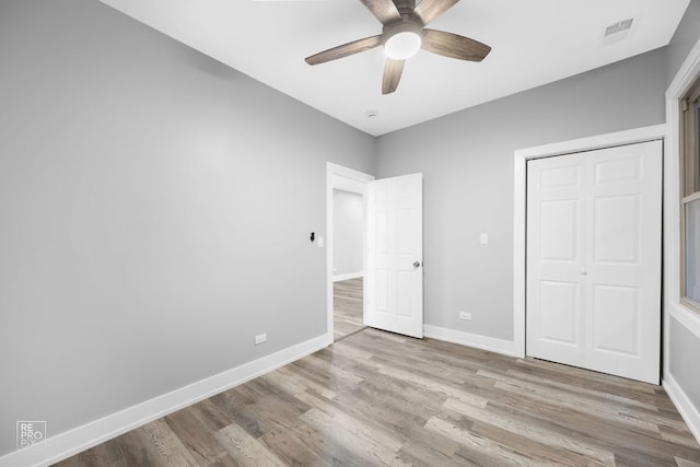 unfurnished bedroom with ceiling fan, light wood-type flooring, and a closet