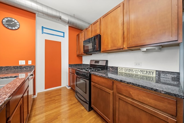 kitchen featuring light hardwood / wood-style floors, dark stone countertops, and stainless steel appliances