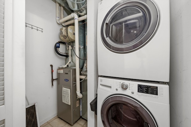 laundry room featuring stacked washer / dryer and light tile patterned floors