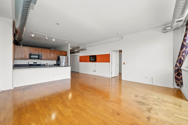 unfurnished living room featuring rail lighting and light hardwood / wood-style flooring