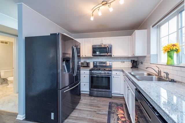 kitchen with decorative backsplash, stainless steel appliances, sink, wood-type flooring, and white cabinets