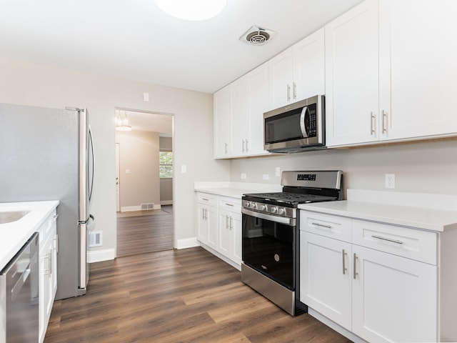 kitchen with appliances with stainless steel finishes, white cabinetry, and dark wood-type flooring