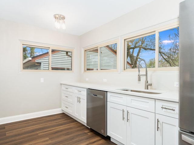 kitchen with appliances with stainless steel finishes, white cabinetry, dark wood-type flooring, and sink