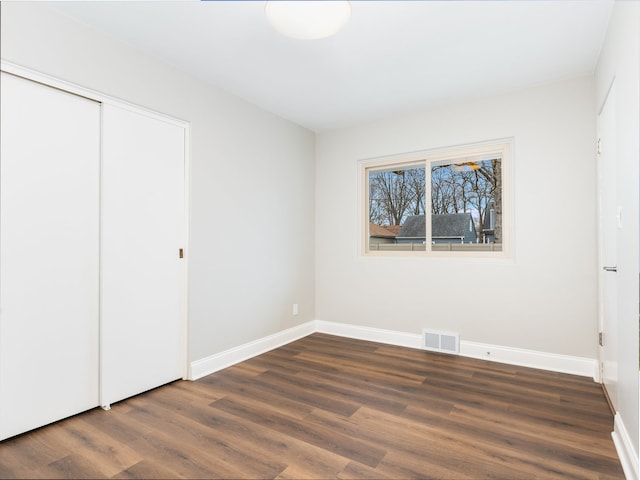 unfurnished bedroom with dark hardwood / wood-style floors and a closet