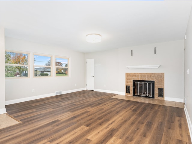 unfurnished living room featuring dark hardwood / wood-style floors and a tile fireplace