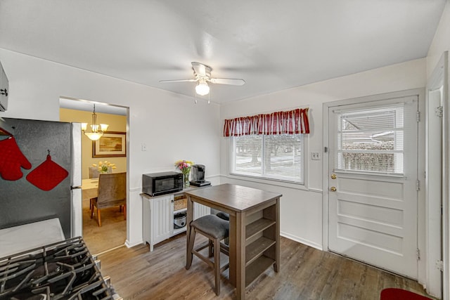 kitchen with stainless steel refrigerator, ceiling fan with notable chandelier, and hardwood / wood-style floors