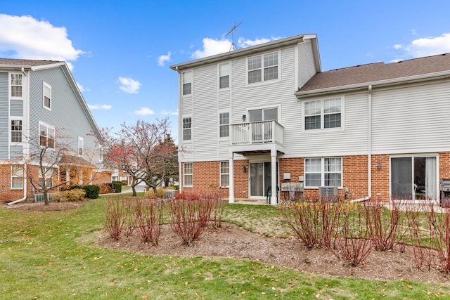 rear view of property with a lawn, a balcony, and central air condition unit