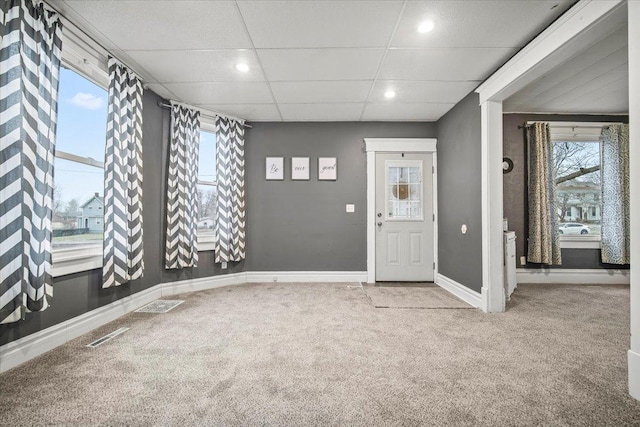 foyer entrance featuring a paneled ceiling and carpet flooring