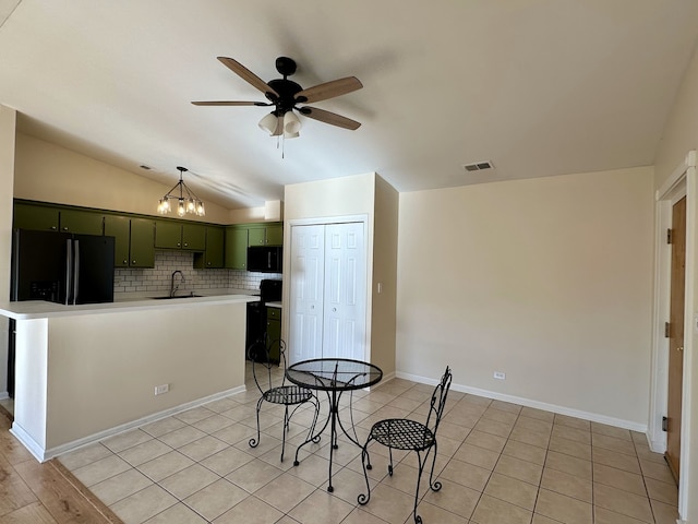 kitchen featuring backsplash, black appliances, sink, green cabinetry, and vaulted ceiling