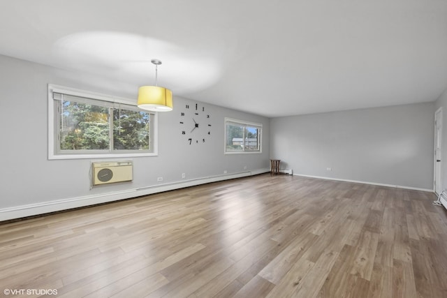 unfurnished living room with a baseboard heating unit, a wall mounted AC, and light wood-type flooring